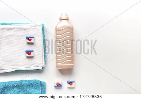 Bright towels pile with washing powder in laudry set on white table background top view mock-up