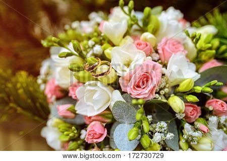 wedding rings at beautiful wedding bouquet with roses