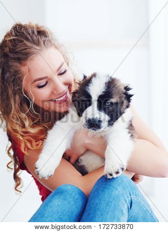 beautiful woman playing with cute caucasian shepherd puppy dog