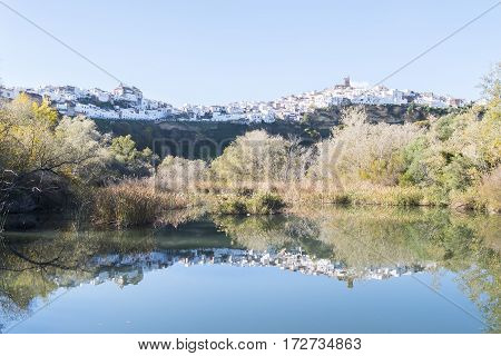 Panoramic of Arcos de la Frontera reflected in the river white town built on a rock along Guadalete river in the province of Cadiz Spain