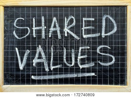 The words Shared Values written by hand in white chalk on a blackboard as a reminder to adopt the core values of your business