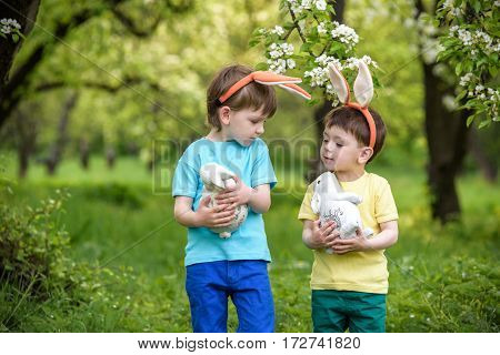 Two Little Kids Boys And Friends In Easter Bunny Ears During Traditional Egg Hunt In Spring Garden,
