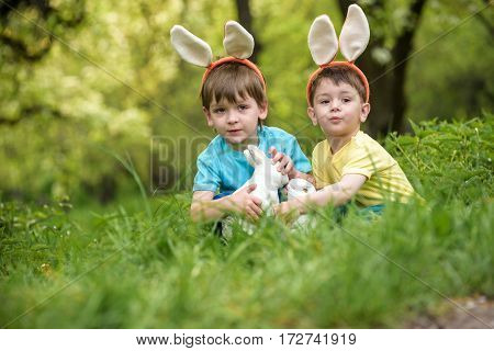 Two Little Kids Boys And Friends In Easter Bunny Ears During Traditional Egg Hunt In Spring Garden,