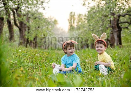 Two Little Kids Boys And Friends In Easter Bunny Ears During Traditional Egg Hunt In Spring Garden,