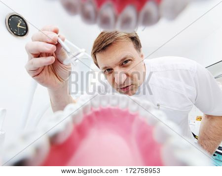 Stomatology. Dentist over open patient's mouth looking in teeth. Inside vew