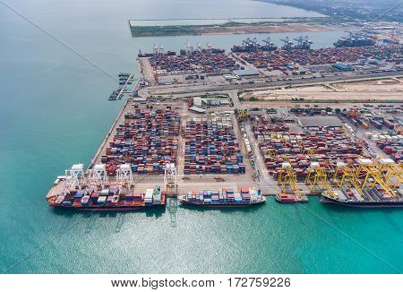 container ship in import export and business logistic. By crane Trade Port Shipping. Tugboat assisting cargo to harbor. Aerial view.