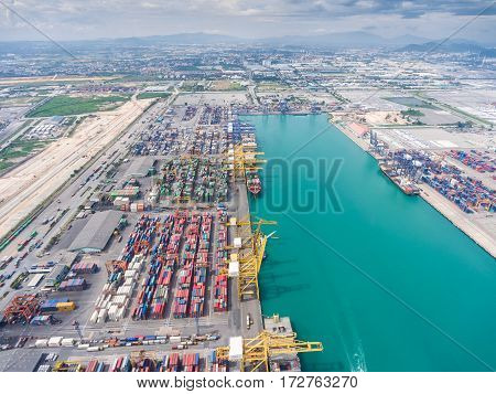 container ship in import export and business logistic. By crane Trade Port Shipping. Tugboat assisting cargo to harbor. Aerial view.