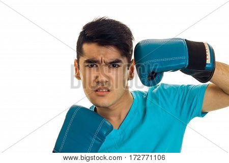 portrait of angry brunette boxer sportsman in blue gloves looking at the camera isolated on white