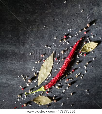 Red Pepper Pungent Spices And Bay Leaf On The Black Tree. View From Above.