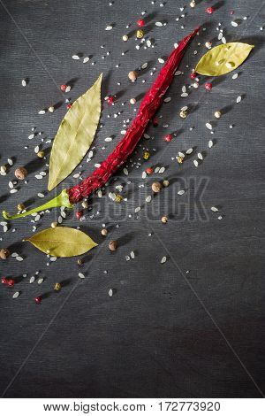 Red Pepper Pungent Spices And Bay Leaf On The Black Tree. View From Above.