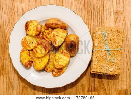 Delicious crispbread tied with organic blue thread on wooden oak table next to baked patatoes