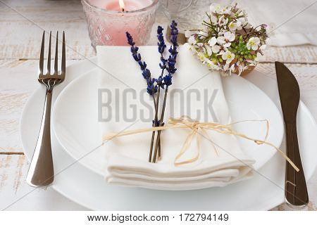 Romantic table setting wedding lavender white small flowers plates napkin lit candle wood table outdoors kinfolk authentic elegant