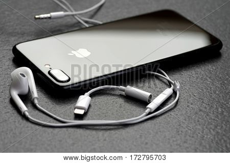 Koszalin, Poland - February 22, 2017: Black iPhone 7 Plus on stone table. Devices displaying the applications on the home screen. The iPhone 7 Plus is smart phone with multi touch screen produced by Apple Computer