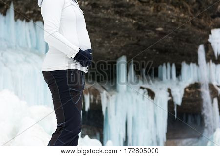 Closeup of female hands holding pregnant belly on winter background. Active pregnancy.