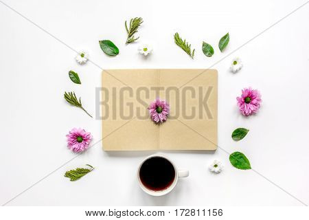 Flower petals, cup of coffee and brown craftpaper copybook on table background top view mock up