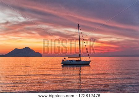 Sailboat sunset silhouette is a sailboat sailing along the water with a colorful purple and pink night sky in the background