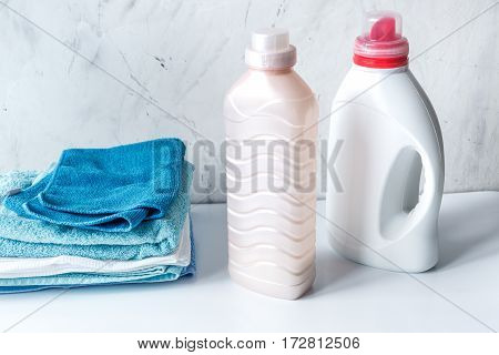 laundry set with bright towels and plastic bottels of detergent on white table background