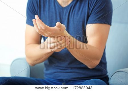 Young man suffering from pain in wrist, closeup
