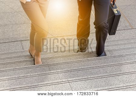 Businessman and Business woman walking up stairs with bags to office.