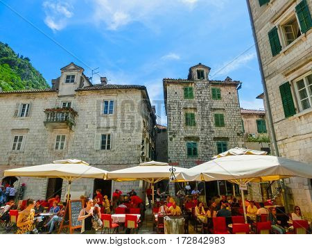 Kotor, Montenegro - May 07, 2014: People sittiing at cafe on St. Luke's square surrounded by traditional stone houses at Kotor's Old Town, Montenegro on May 07, 2014. People walking