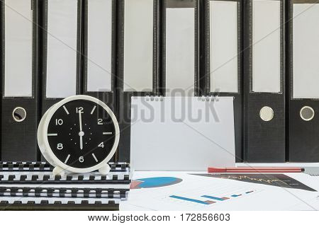 Closeup white clock for decorate in 6 o'clock desk of officer with work paper and document file in office room textured background in work concept