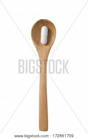 White capsule on a wooden spoon isolated on the white background