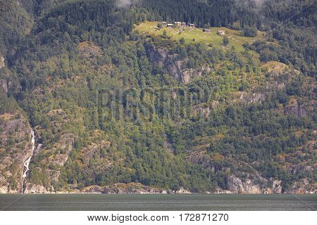 Norwegian fjord landscape with waterfall and houses. Sorfjorden. Norway. Horizontal