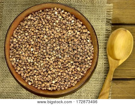 Buckwheat groats in a bowl and wooden scoop with buckwheat