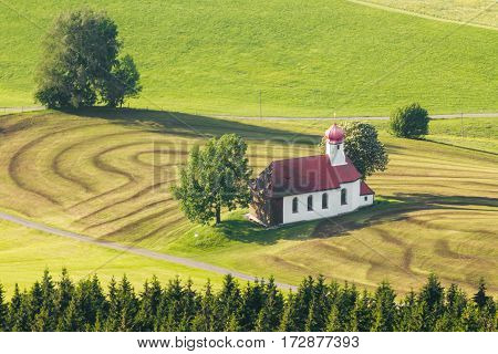 Beautiful bavarian chapel in lovely rural countryside. Pasture landscape with meadows and trees.