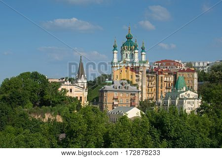 General view of the Andriyivskyy Descent with the Saint Andrew's Church. Foreground - spring foliage. Background - blue sky.
