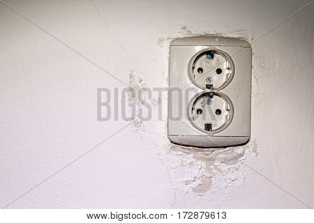old electrical socket mounted on wall damaged by water leakage