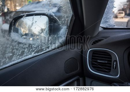 Winter view from side window of car covered with droplets and snowfakes