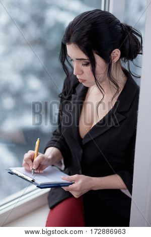 Girl in office writing notes near window