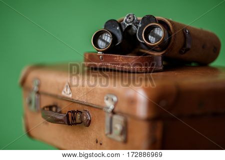 Vintage binoculars on an old suitcase. Shallow depth of field. Travel concept.