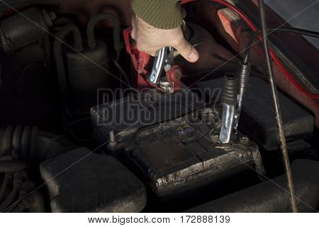Mechanic jumper cables connected to a discharged battery.
Firing the car in the winter by the jumper cables.