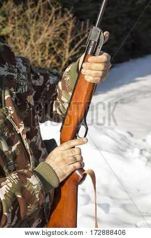 Hunter dressed in camouflage with pneumatic gun, rifle Man's hands holding a flask with a long gun hunting.