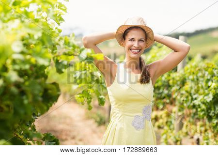 Portrait of female vintner in hat standing in vineyard