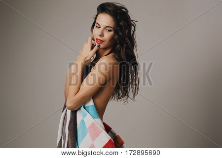 Fashion photo of beautiful and young lady in swimsuits posing in studio, holding colorful towel