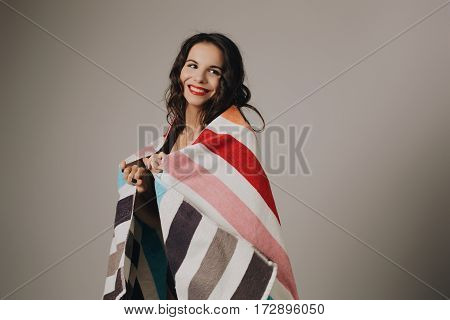 Fashion photo of beautiful and young lady in swimsuits posing in studio, holding colorful towel