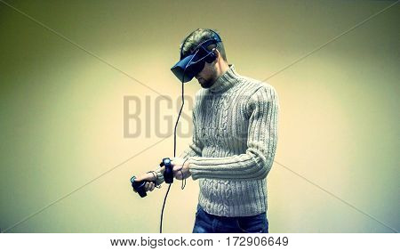 Man in helmet virtual reality plays game. Man uses VR-headset display with headphones for virtual reality game in office. High-tech devices. Augmented reality device creating virtual space