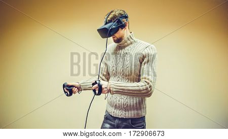 Man in helmet virtual reality plays game. Man uses VR-headset display with headphones for virtual reality game in office. High-tech devices. Augmented reality device creating virtual space