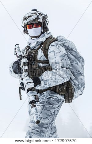 Winter arctic mountains warfare. Action in cold conditions. Trooper with weapons in forest somewhere above the Arctic Circle