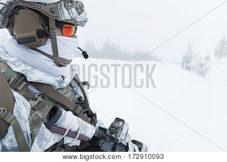 Winter arctic mountains warfare. Action in cold conditions. Trooper with weapons in forest somewhere above the Arctic Circle. Profile, side view