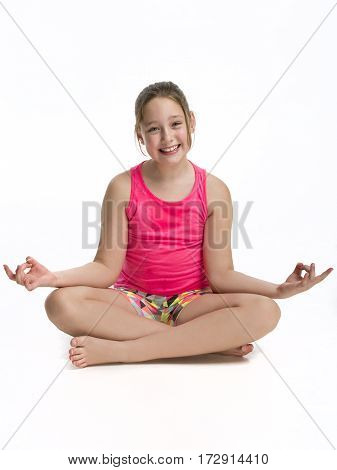 Young Tween girl sitting in a yoga pose on a white background