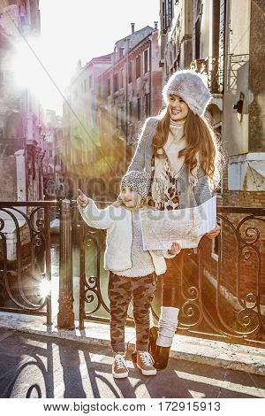 Venice. Off the Beaten Path. Full length portrait of happy young mother and child tourists in Venice Italy in the winter with map