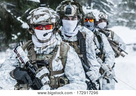 Winter arctic mountains warfare. Action in cold conditions. Squad of soldiers with weapons in forest somewhere above the Arctic Circle