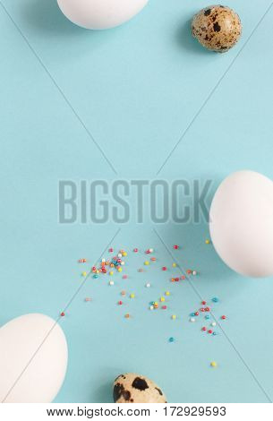 Easter decoration white chicken eggs and quail eggs on a light blue background with space for text vertical image