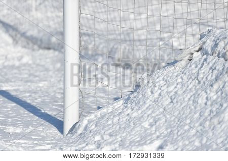 Detail with a soccer goalpost covered by snow