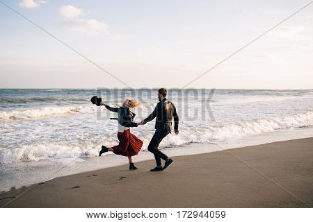 A guy and a girl running through the waves of the sea