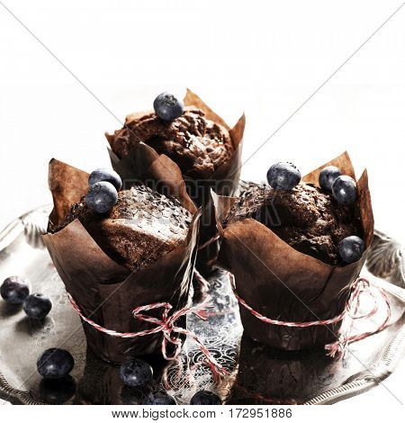Chocolate cupcake on an antique silver tray with blueberry on the top. Delicious food with nice table-ware. Food concept.